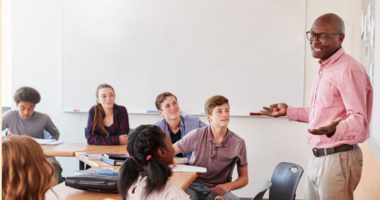 A man standing and making a presentation in front of seated students